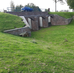 Photo of green field with the floodgate on the Zuiddijk in the Beemster with a car on top